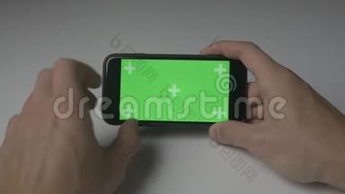 使用智能手机触摸的特写镜头，白色<strong>桌面背景</strong>上有绿色屏幕彩色键